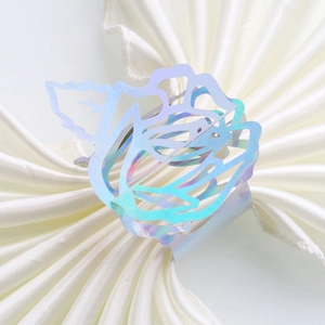 Detail of laser-cut rose napkin ring with iridescent holographic finish on white satin