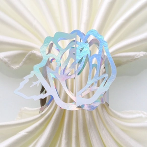 Macro detail of holographic paper napkin ring with laser-cut rose pattern for wedding decor