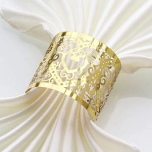 Detail of laser-cut gold heart napkin ring on white satin fabric for wedding table