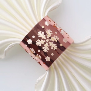 Macro view of rose gold hollow snowflake napkin ring on white satin fabric