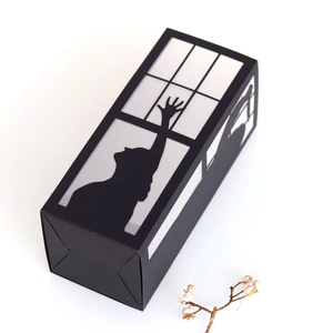 Detailed macro view of black paper lantern featuring silhouette shadow art on white background