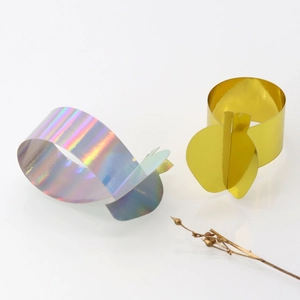 Detail of mirror-finish gold apple napkin ring and iridescent laser metal napkin holder set