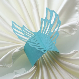 Detail of light blue laser-cut butterfly wing napkin ring on white satin fabric