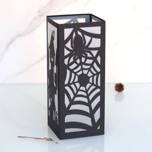 Detail of laser-cut black paper lantern with spider web and haunted castle patterns