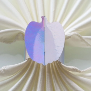 Close-up of a pumpkin-shaped napkin ring with iridescent metallic finish on a white napkin