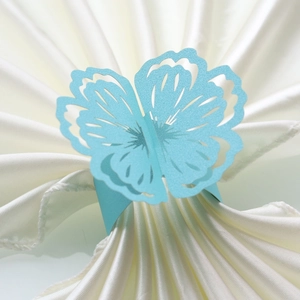 Macro view of laser-cut light blue floral paper napkin ring on white satin fabric