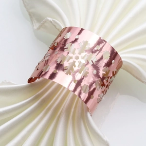 Detail of rose gold snowflake napkin ring with intricate laser cutouts on white fabric