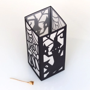 Detail of laser-cut black paper lantern with spider webs and haunted castle designs