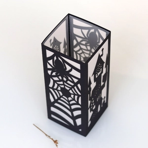Detail of Halloween paper lantern with black spider web and spooky castle cut-out patterns