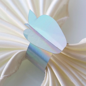Macro detail of iridescent butterfly napkin ring with multi-layer wings on silk fabric