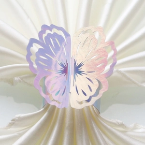 Close-up of holographic laser-cut butterfly napkin ring on a white fabric napkin