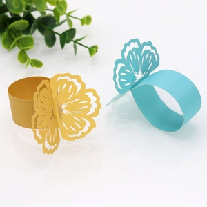 Detail of laser-cut paper napkin rings in champagne gold and light blue flower shapes