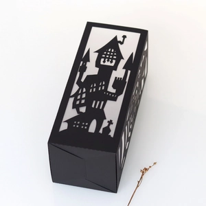 Detail of laser-cut black Halloween gift box with haunted house and bat patterns