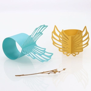 Detail showing blue and gold laser-cut paper napkin rings with angel wing pattern
