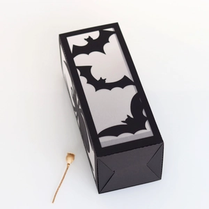 Close-up of a black Halloween paper lantern with laser-cut bat patterns and matte finish