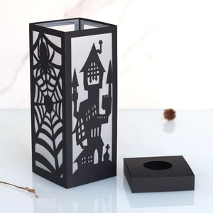 Halloween black paper lantern with spider web and castle cutouts on white marble background