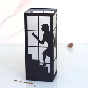 Detailed view of black paper lantern featuring a girl climbing stairs cutout with light