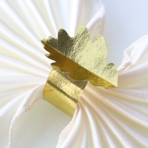 Gros plan d'un rond de serviette feuille dorée sur satin blanc pour décor de Thanksgiving