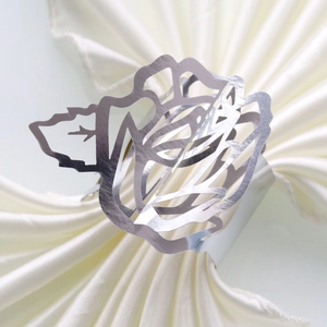 Detailed view of silver hollow rose napkin ring on a beige satin napkin for wedding decor