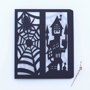 Detail of laser-cut Halloween invitation with spider web and gothic castle silhouette