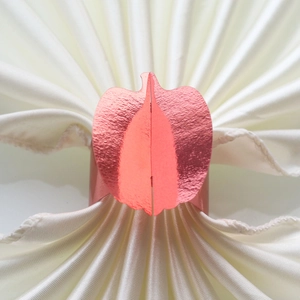 Detailed view of rose gold pumpkin napkin ring on elegant white satin fabric