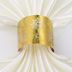 Close-up of golden snowflake napkin ring with laser-cut hollow pattern and shiny finish