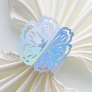 Macro shot of laser holographic hollow butterfly napkin ring on white satin fabric