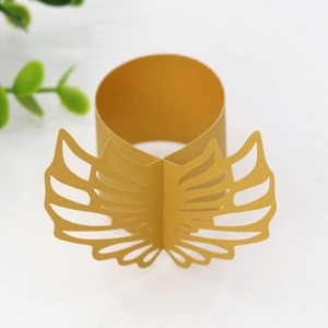 Detail of laser-cut golden paper napkin ring featuring elegant symmetrical hollow wings