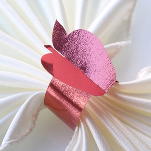 Detailed close-up of rose gold butterfly napkin ring on white satin fabric