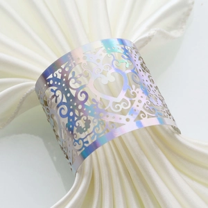 Detail of laser-cut iridescent heart napkin ring on a white satin fabric for weddings