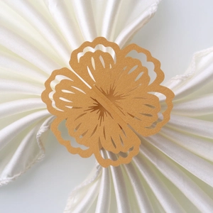 Macro detail of laser-cut pearl paper flower napkin rings in elegant gold for weddings