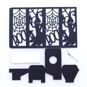 Flat lay of laser-cut black paper Halloween decorations featuring BOO and spider web motifs