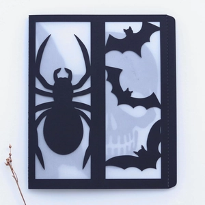 Detail view of laser-cut black Halloween card featuring spider and bat motifs with inner liner