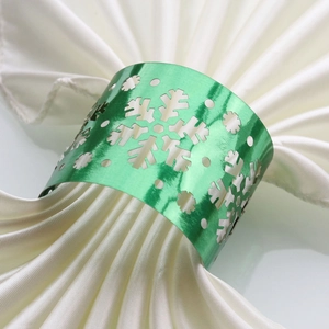 Detail of green metallic snowflake napkin ring with a polished mirror finish and cutouts