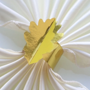 Rond de serviette feuille dorée élégant sur satin blanc pour décoration de table mariage