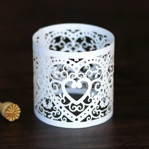 Detailed laser cut white cardstock candle wrap with intricate heart and scroll patterns