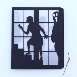 Macro detail of Halloween black paper lantern showing cutout ghost and girl silhouette