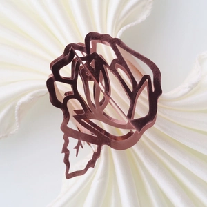 Macro view of rose gold hollow rose napkin ring on pleated white cloth napkins