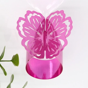 Detail of rose pink napkin ring featuring hollow butterfly design with metallic finish