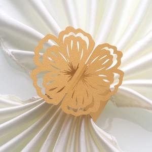 Detail of laser-cut gold paper napkin ring with elegant floral pattern on white silk