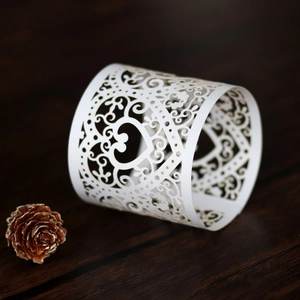 Detailed view of laser-cut white heart and vine pattern on paper napkin ring