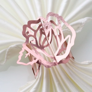 Macro detail of rose gold floral napkin ring with hollow rose design on white satin fabric