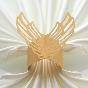 Detail of laser-cut gold pearlescent paper napkin ring with intricate wing patterns