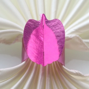 Macro detail of leaf-shaped pink napkin ring with a brushed metallic texture finish
