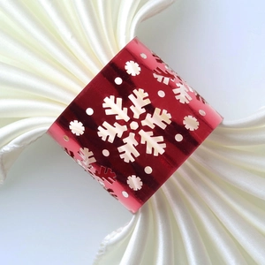 Macro detail of red metallic snowflake napkin ring with intricate laser-cut design