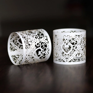 Macro detail of laser-cut heart pattern pearl white napkin rings on dark wood surface