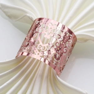 Macro shot of rose gold heart napkin ring with laser-cut floral patterns on white silk