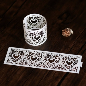 Detail of white laser-cut paper cupcake wrappers with elegant heart and vine patterns