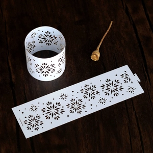 Detail showing laser-cut silver snowflake paper napkin ring on dark wood background