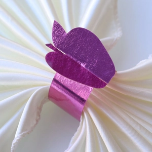 Macro shot of purple double leaf metal napkin ring on white satin fabric napkin